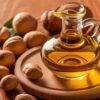 Close-up view of Cold-Pressed Groundnut Oil in a glass bottle, surrounded by whole Groundnuts.