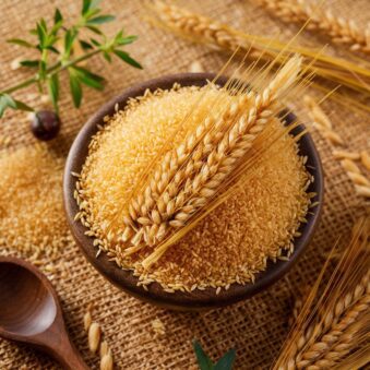 Close-up of Foxtail Millet grains arranged with fresh herbs and a rustic wooden spoon.